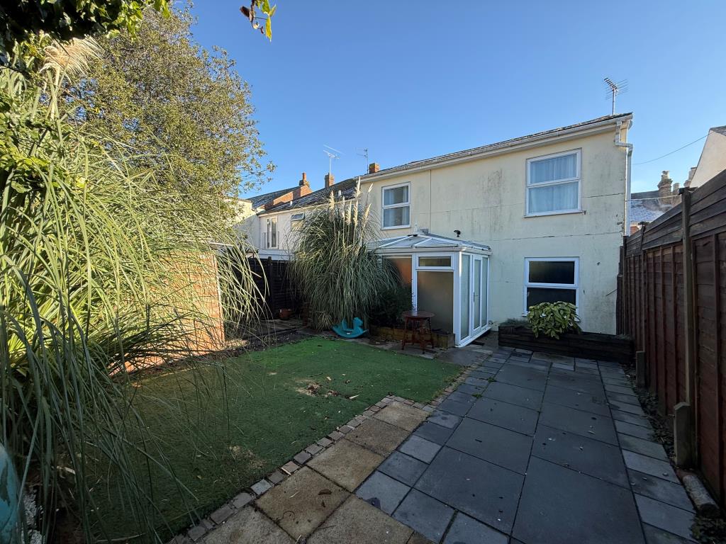 Lot: 141 - DETACHED FOUR-BEDROOM HOUSE FOR IMPROVEMENT - Back garden with astroturf showing back of house